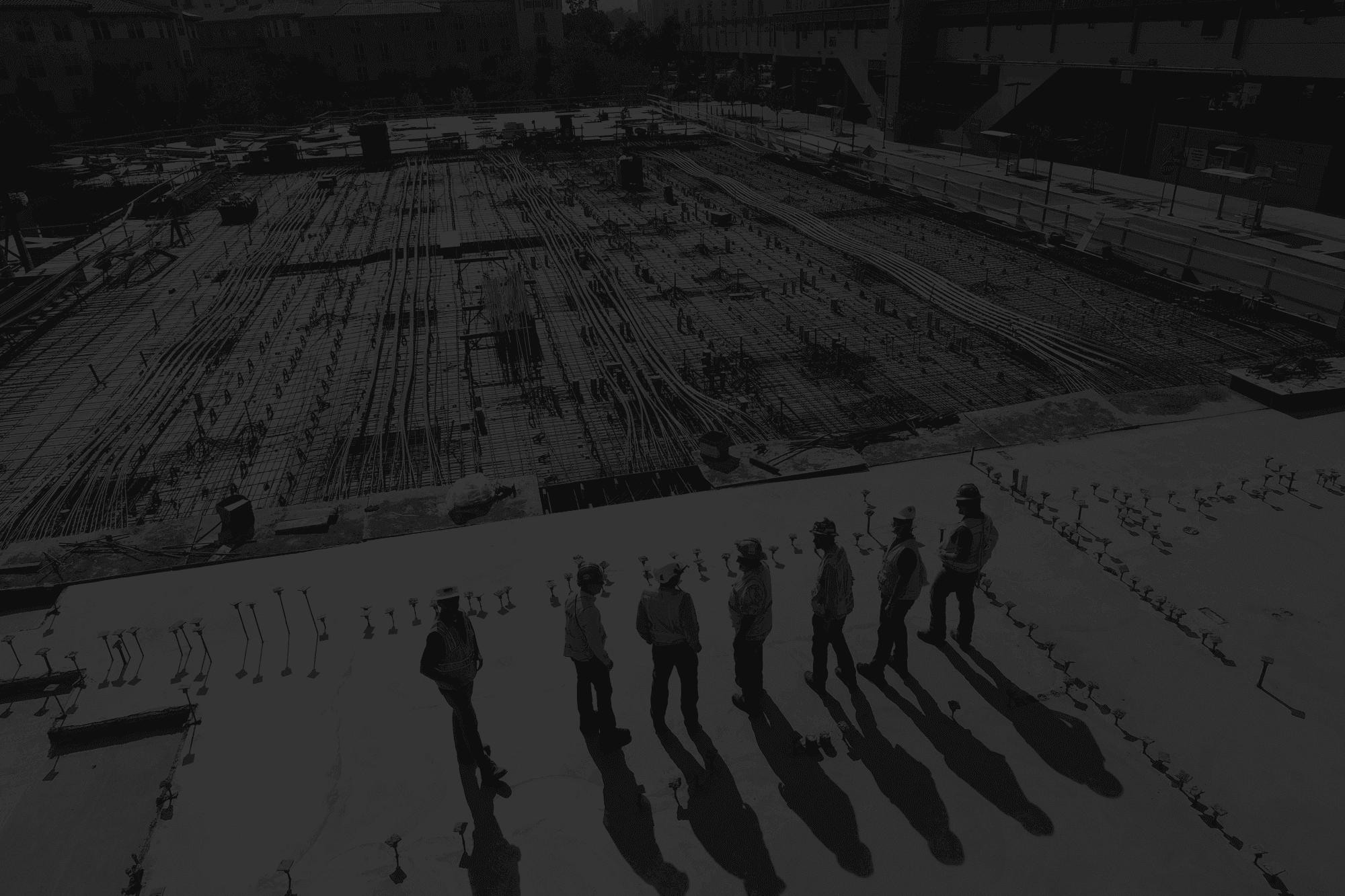 Project team inspecting a construction slab with visible rebar and conduit